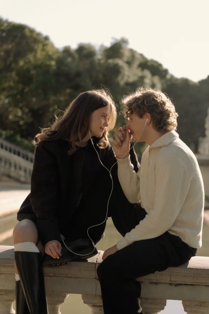 A couple shares headphones and a loving gaze by the water in Barcelona during a couples & engagements photoshoot.