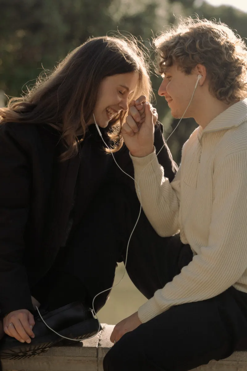 A couple shares headphones and laughter, holding hands during a candid couples & engagements session in Barcelona.
