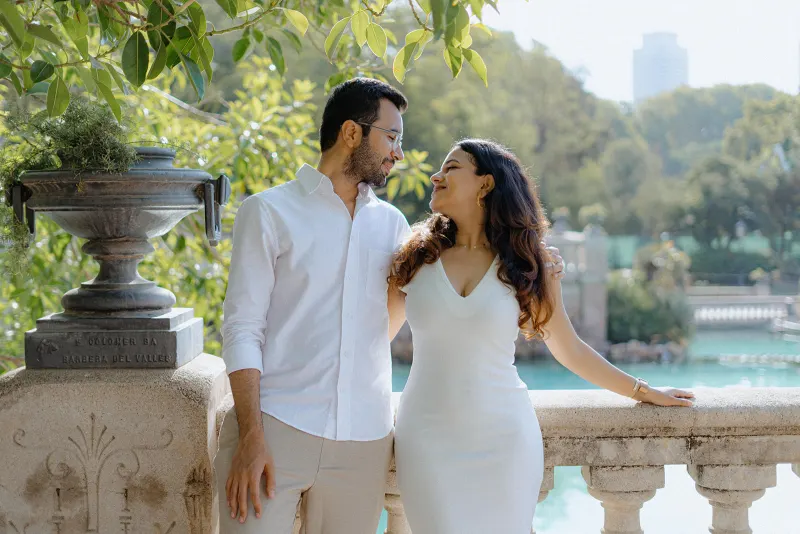 A couple smiles lovingly at each other on a sunny terrace during their surprise proposal photoshoot in Parc de la Ciutadella.