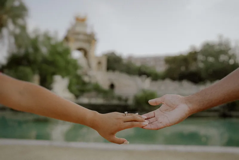 A couple’s hands reach for each other, engagement ring visible, during a romantic session at Parc de la Ciutadella.