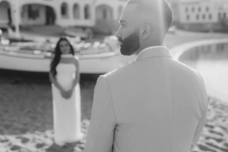 A groom-to-be turns to see his partner on the beach during a surprise proposal photoshoot.