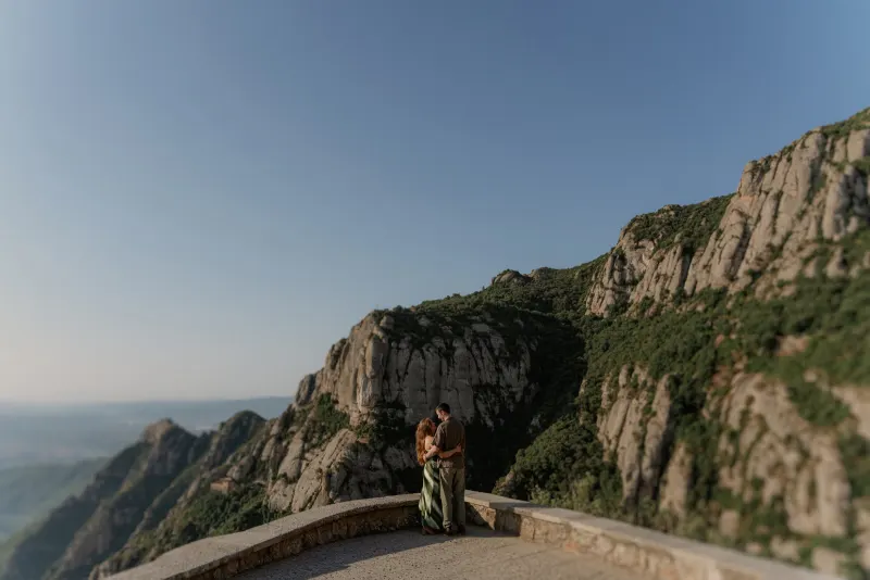 A wide mountain view frames Tim and Megan embracing at the lookout.