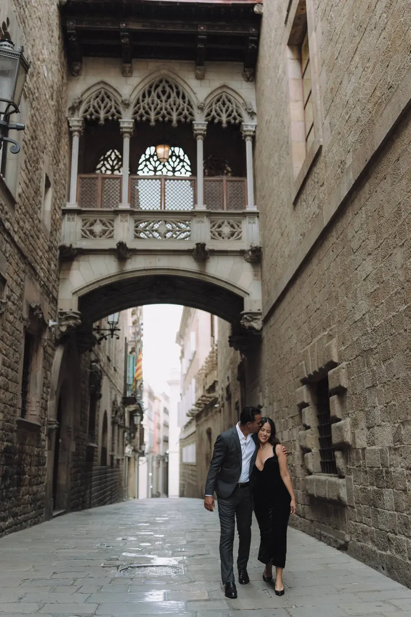 A wide view of Ashley and Edgar walking beneath Pont del Bisbe in the Gothic Quarter.