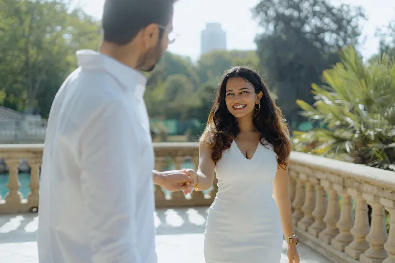 A woman beams with happiness as her partner takes her hand during a surprise proposal photoshoot in Parc de la Ciutadella.