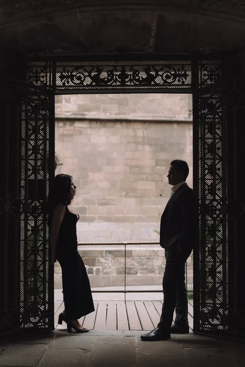 Ashley and Edgar appear in silhouette inside a dark Gothic archway in Barcelona.