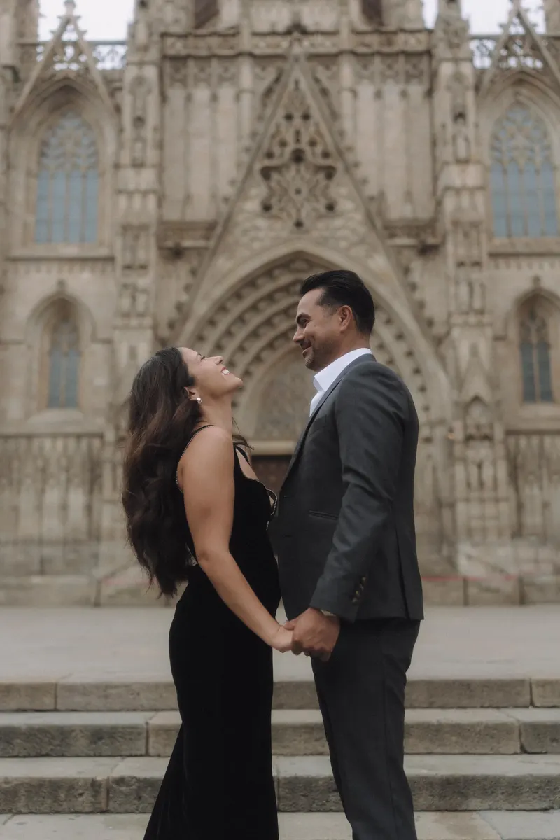 Ashley and Edgar hold hands and smile in front of Barcelona Cathedral during their Gothic Quarter photoshoot.