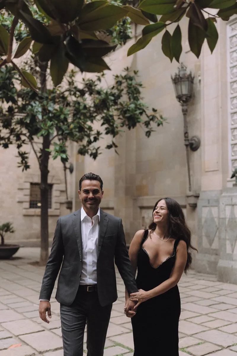 Ashley and Edgar laugh together while walking through a peaceful historic courtyard.