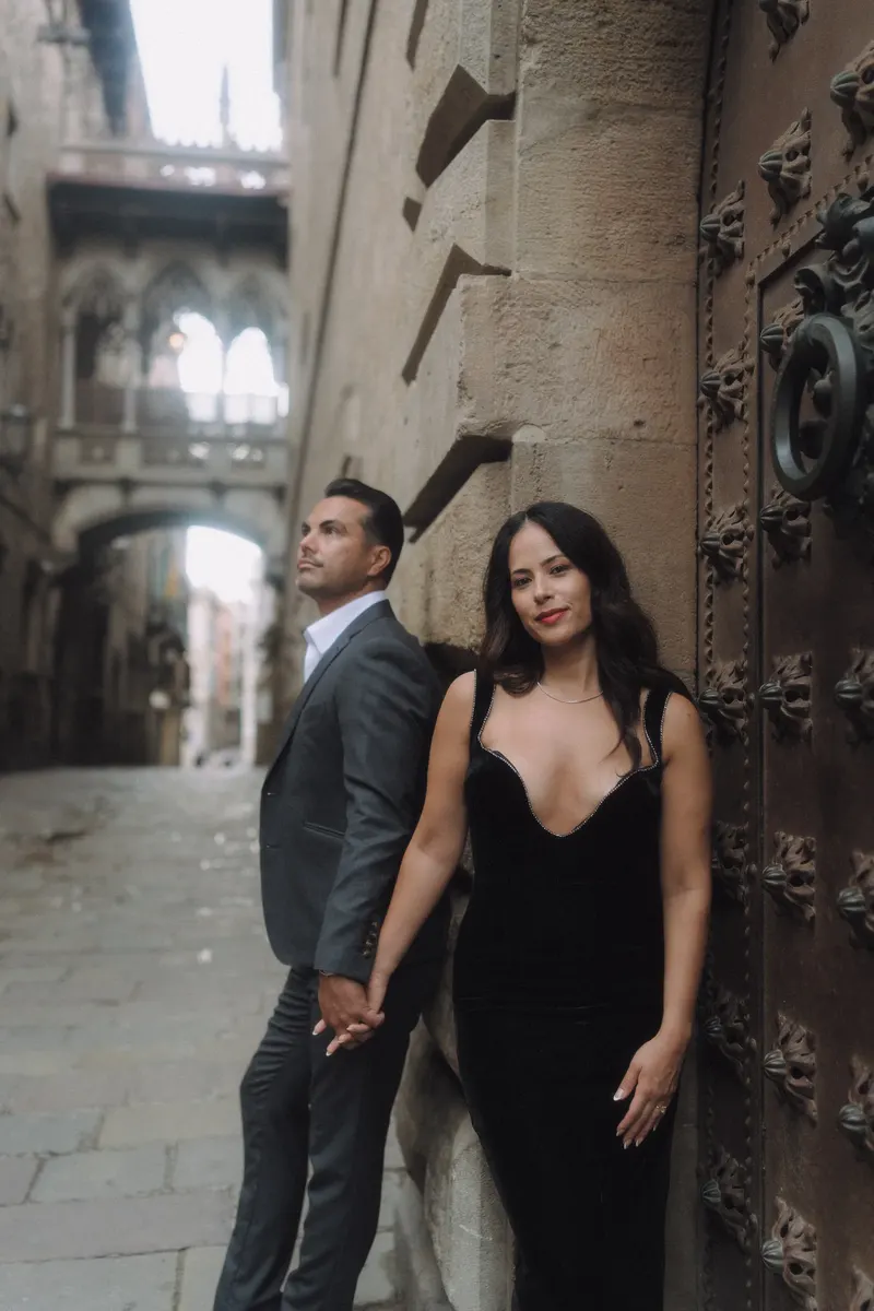 Ashley and Edgar pose together in the narrow Gothic street beneath Pont del Bisbe.