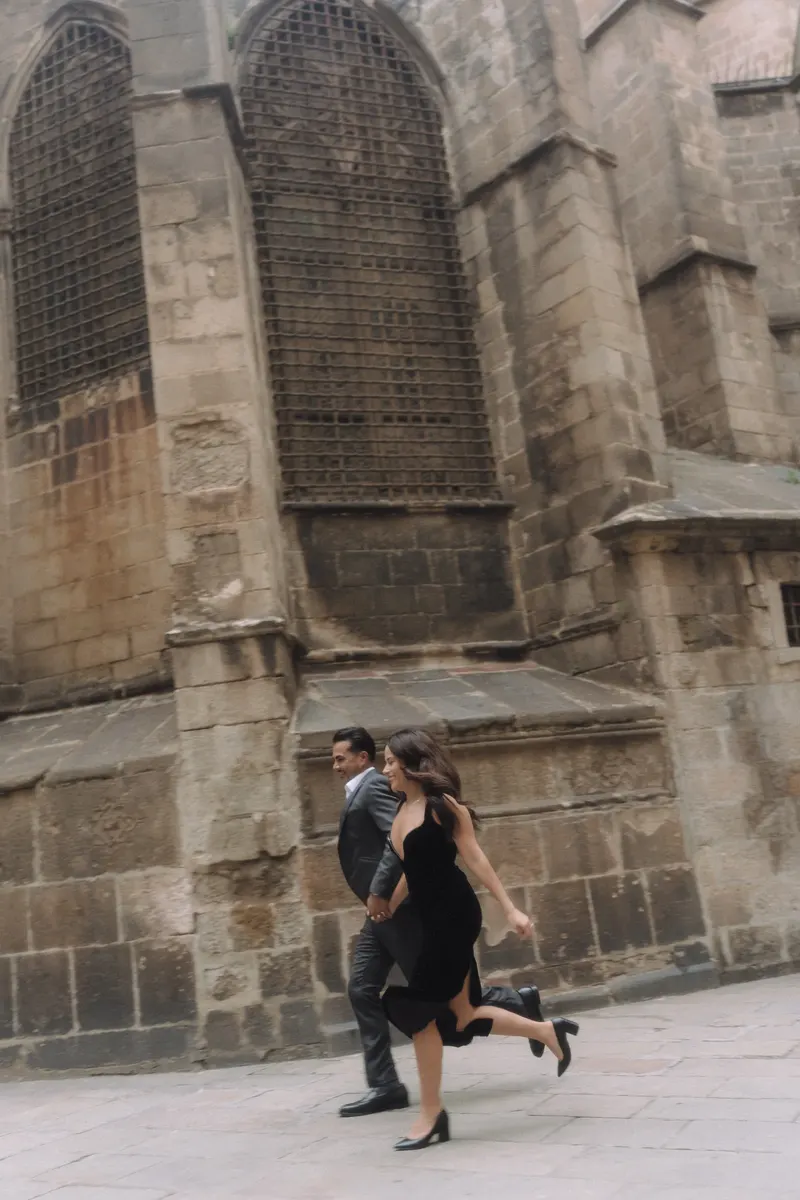 Ashley and Edgar share a playful running moment beside the ancient stone walls of Barcelona.