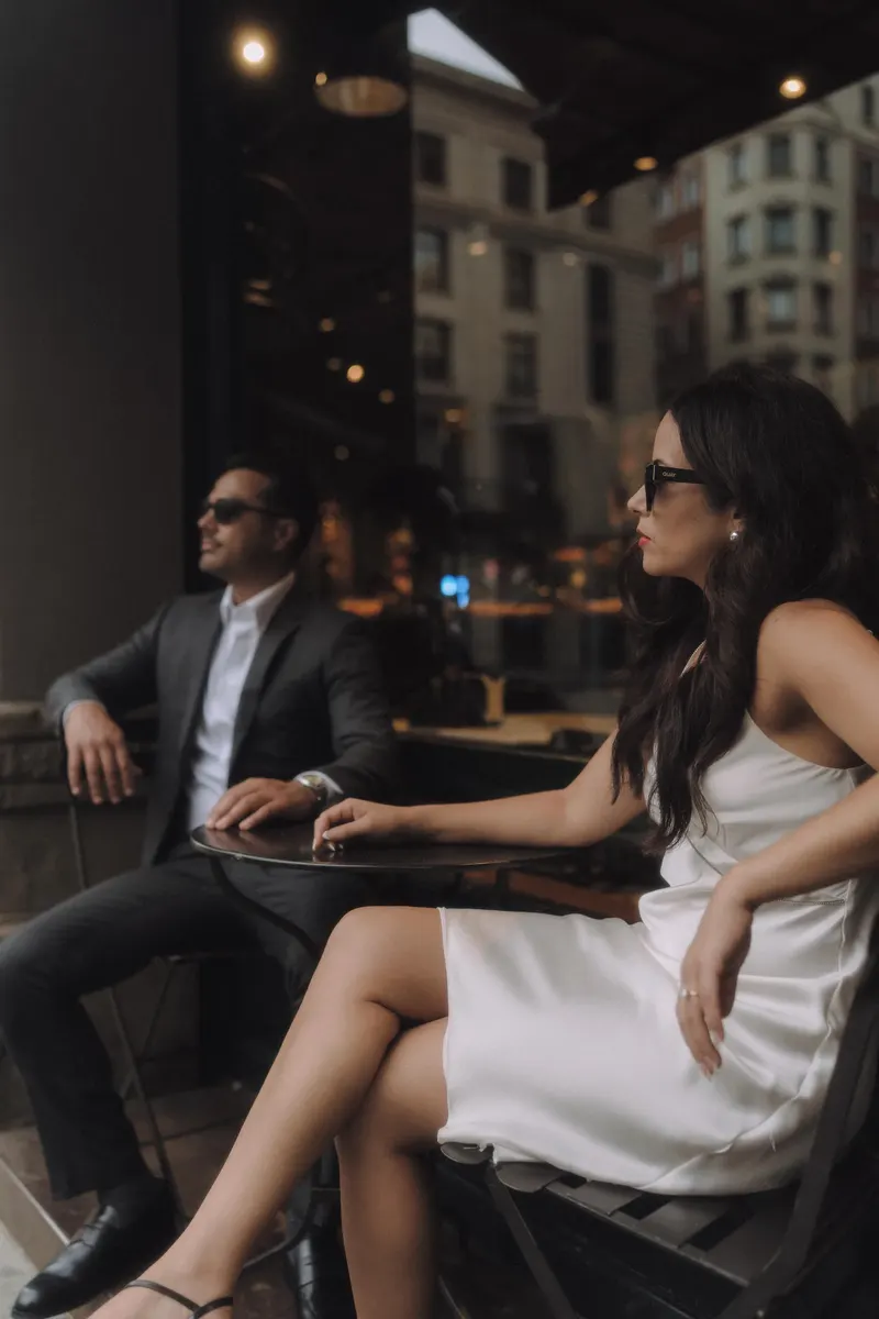 Ashley and Edgar sit at a small cafe table during their Barcelona couple photoshoot.