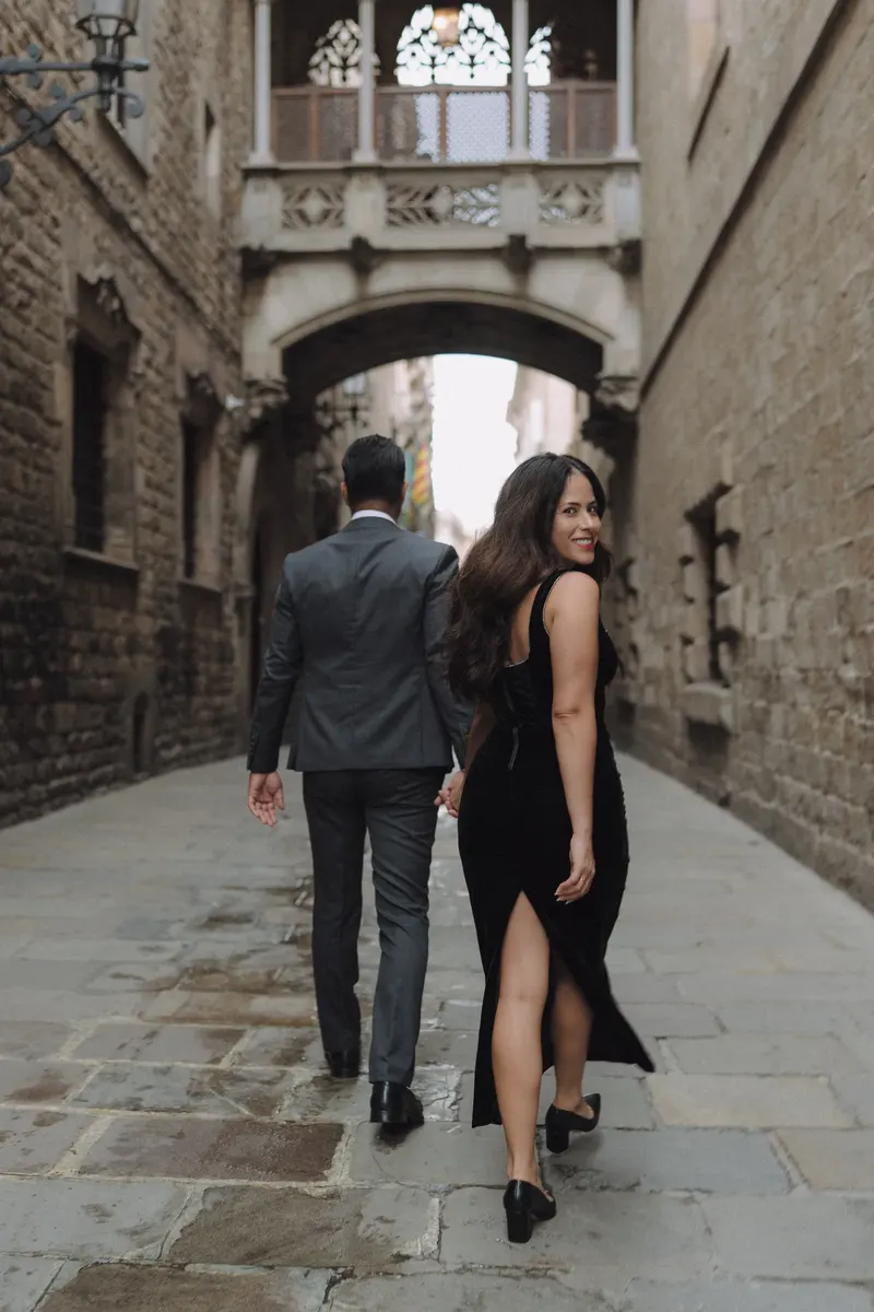 Ashley and Edgar stand close together below the neo-Gothic bridge in Barcelona.