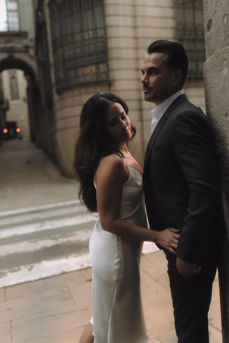 Ashley and Edgar stand close together in soft morning light on a historic Barcelona street.