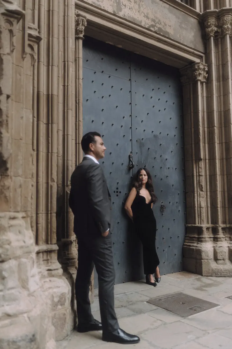 Ashley and Edgar stand on either side of a historic blue doorway in the Gothic Quarter.