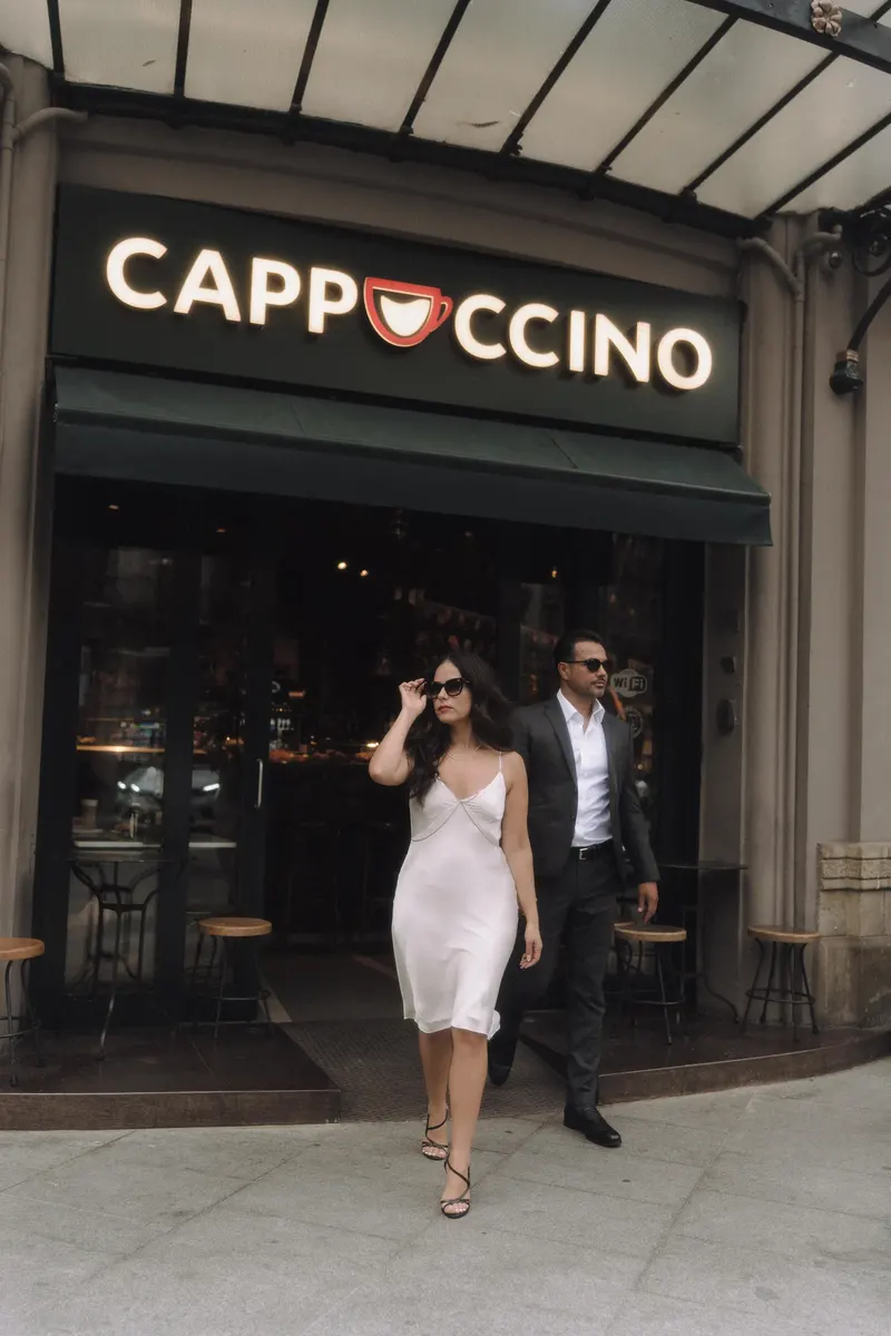 Ashley and Edgar step out of the cafe together in elegant city outfits.