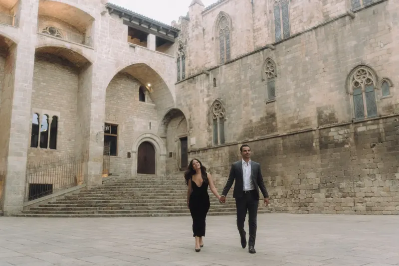 Ashley and Edgar walk across Plaça del Rei during their early morning couple session.