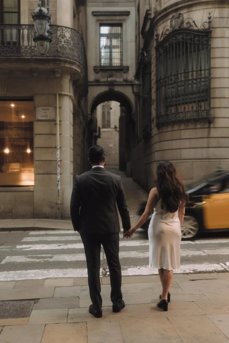 Ashley and Edgar walk away hand in hand toward a cafe in the Gothic Quarter.