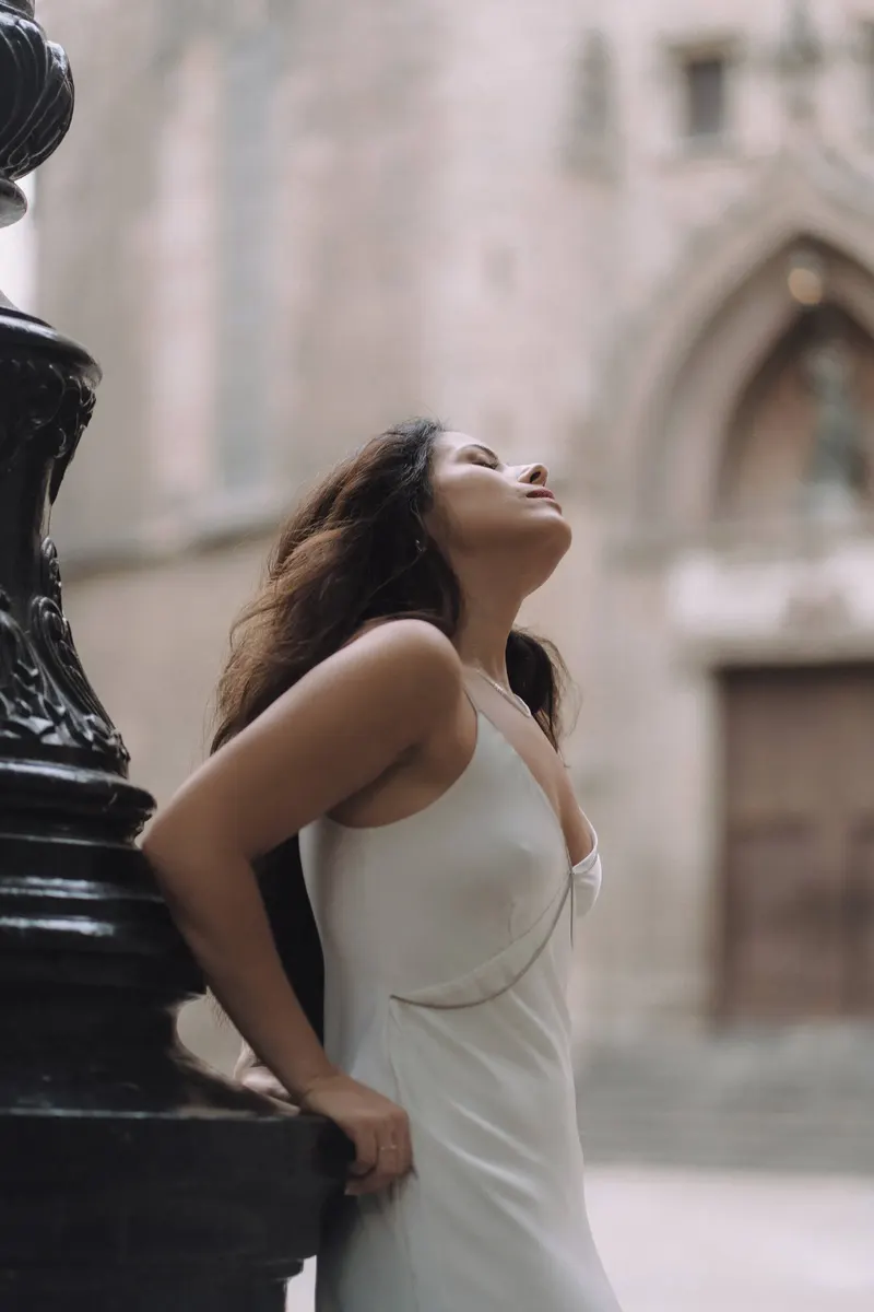 Ashley poses in a white dress beside an ornate black street lamp in Barcelona.
