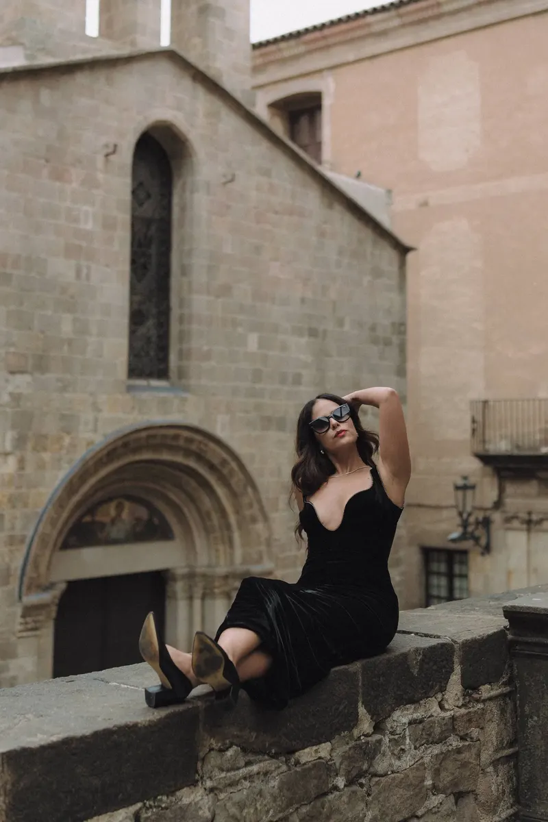 Ashley poses on an old stone wall in a secluded courtyard near Barcelona Cathedral.