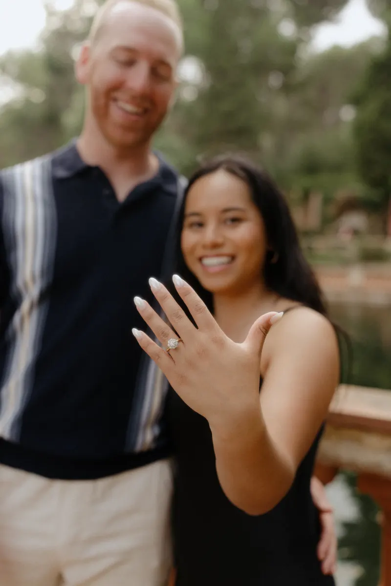 Beaming couple celebrates their engagement as she shows off her ring during a surprise proposal photoshoot in the garden.