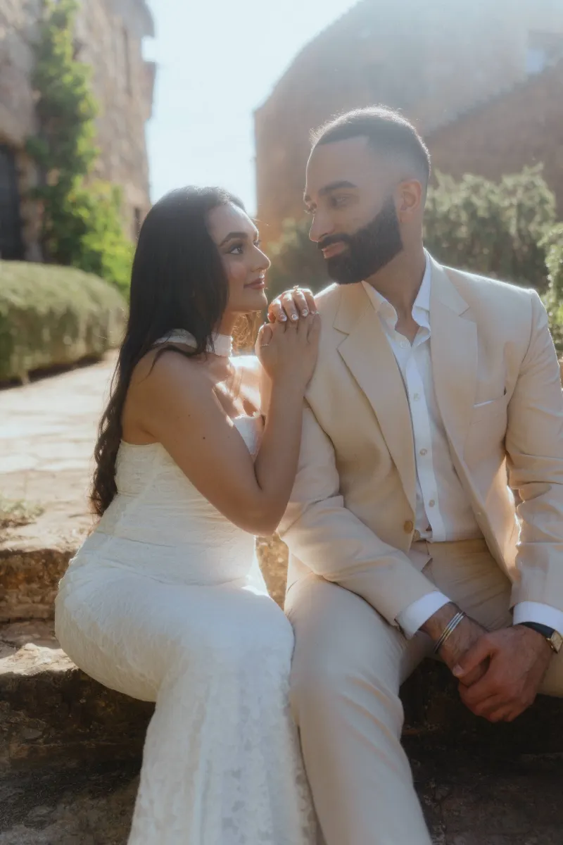 Bride-to-be gazes lovingly at her partner on rustic stone steps during a surprise proposal photoshoot.