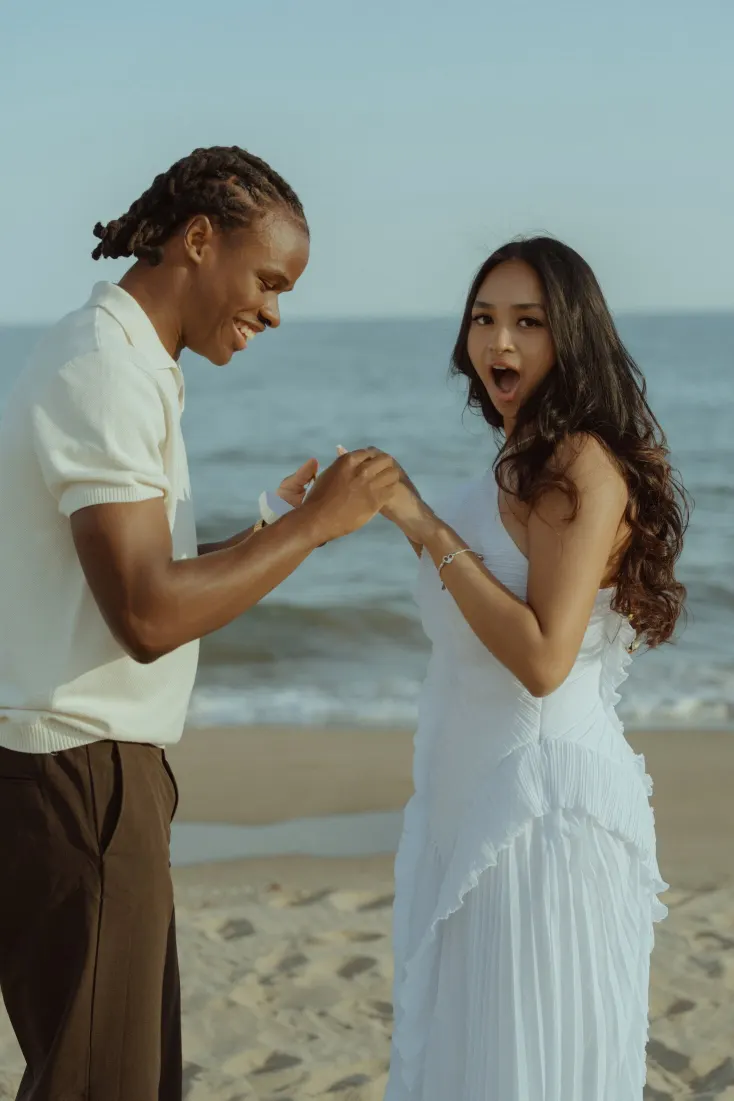 Cheryl reacts with joy while Dexter holds her hand moments after the beach proposal.