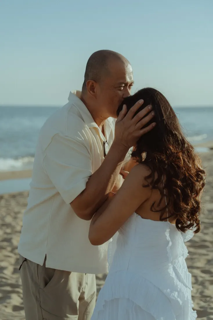 Cheryl receives an emotional embrace from a family member after her surprise proposal on the beach.