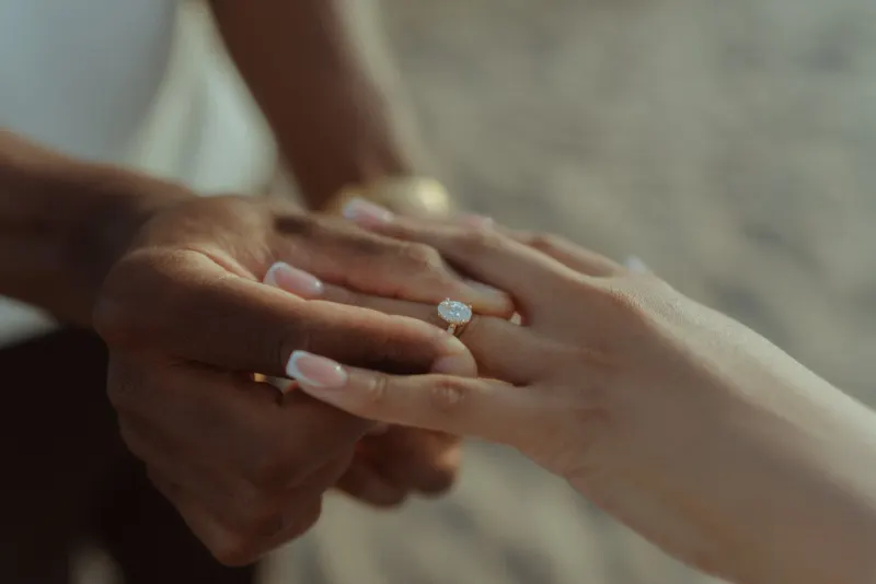 Cheryl’s engagement ring in a close-up photograph captured on the sand at Castelldefels Beach.