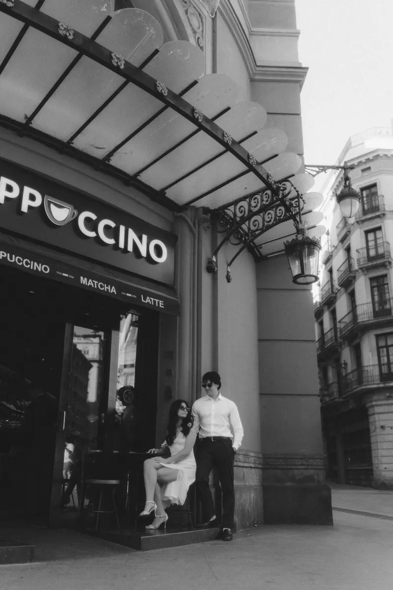 Chic couple shares a relaxed moment outside a café during their couples & engagements photoshoot in the city.