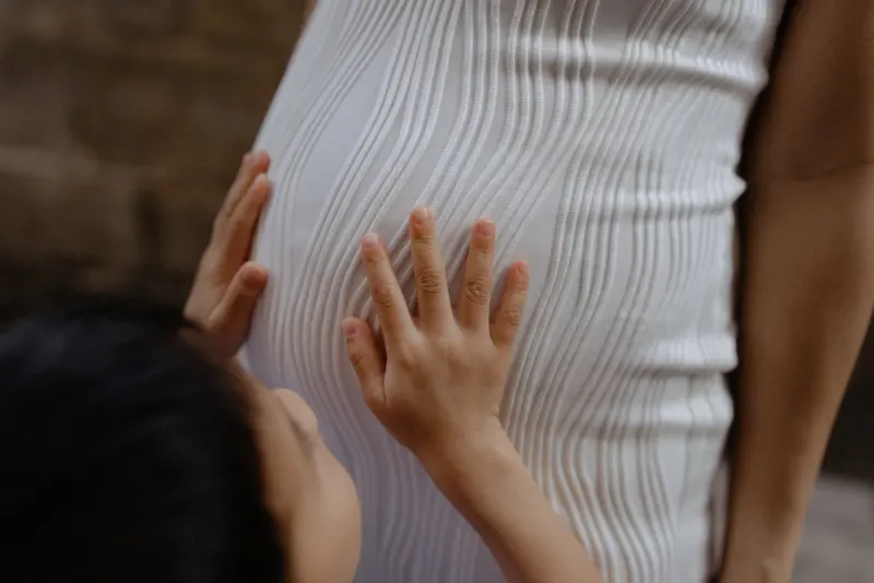 Child gently touching mother’s baby bump during a Vacation Portraits photoshoot in Barcelona’s old town.