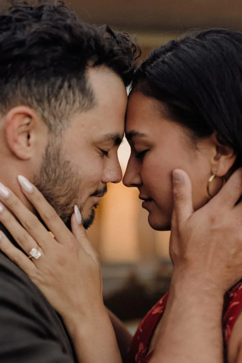 Close portrait of Dan and Sydney touching foreheads with her engagement ring in view.