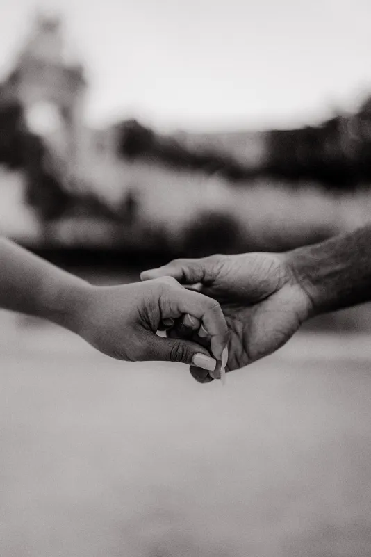 Close-up of a couple gently holding hands, capturing a tender moment during an engagement photoshoot.