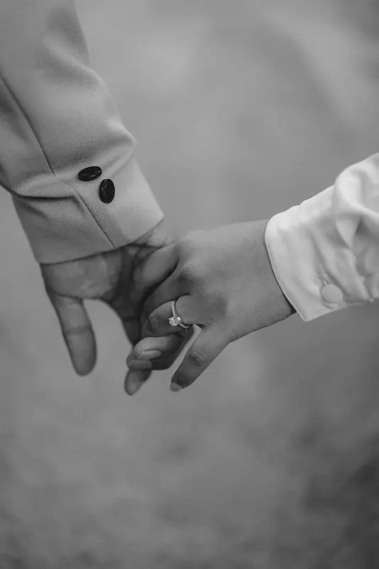Close-up of a couple gently holding hands, engagement ring visible, captured during a couples photoshoot session.