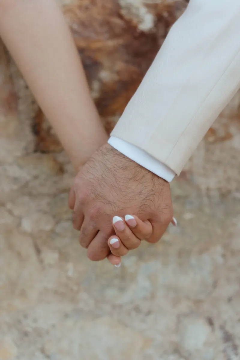 Close-up of a couple holding hands, capturing a tender moment from their surprise proposal photoshoot.