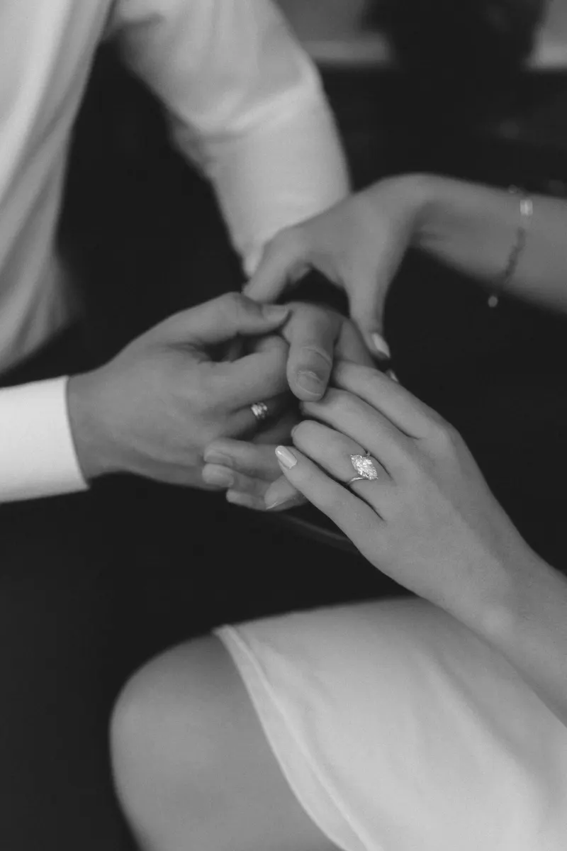 Close-up of a couple holding hands, engagement ring sparkling, capturing a tender moment during their engagement session.