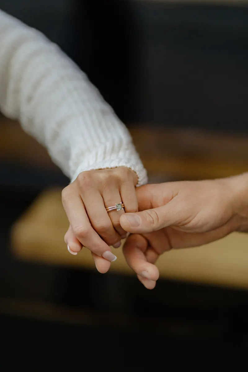 Close-up of a couple holding hands, her engagement ring sparkling during a couples & engagements photoshoot.