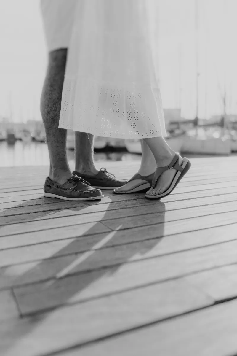 Close-up of a couple’s feet as they share an intimate moment on a marina dock, part of a couples & engagements session.