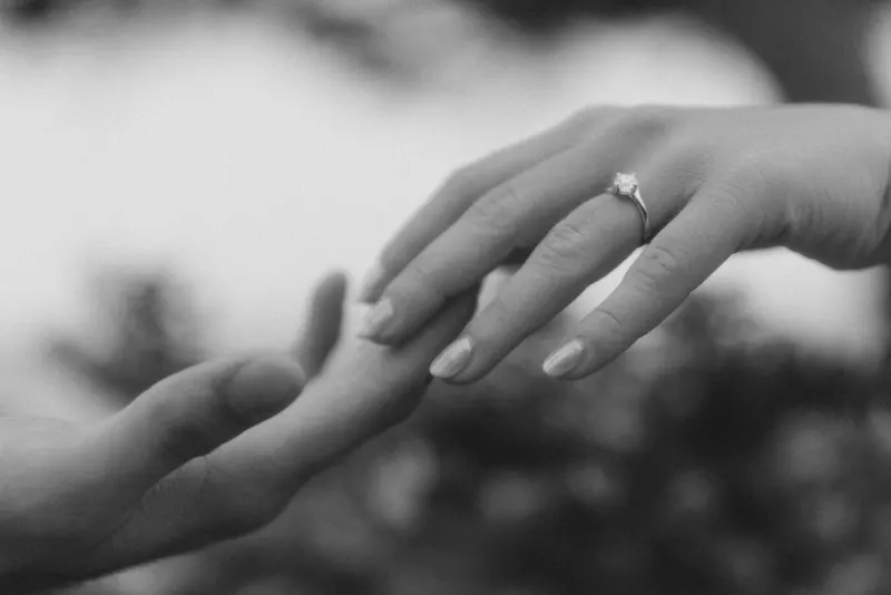 Close-up of a couple’s hands as she shows off her engagement ring during a surprise proposal photoshoot.