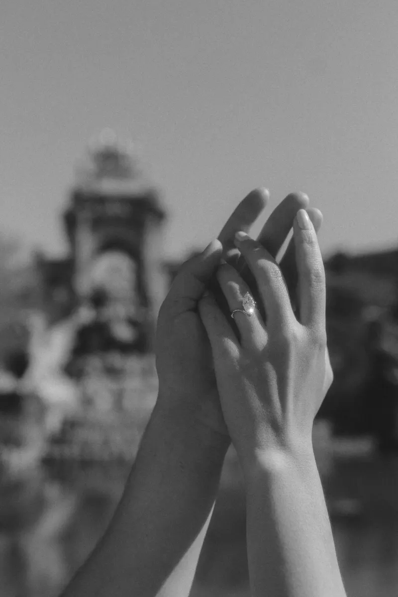 Close-up of a couple’s hands intertwined, engagement ring sparkling during a romantic couples photoshoot outdoors.