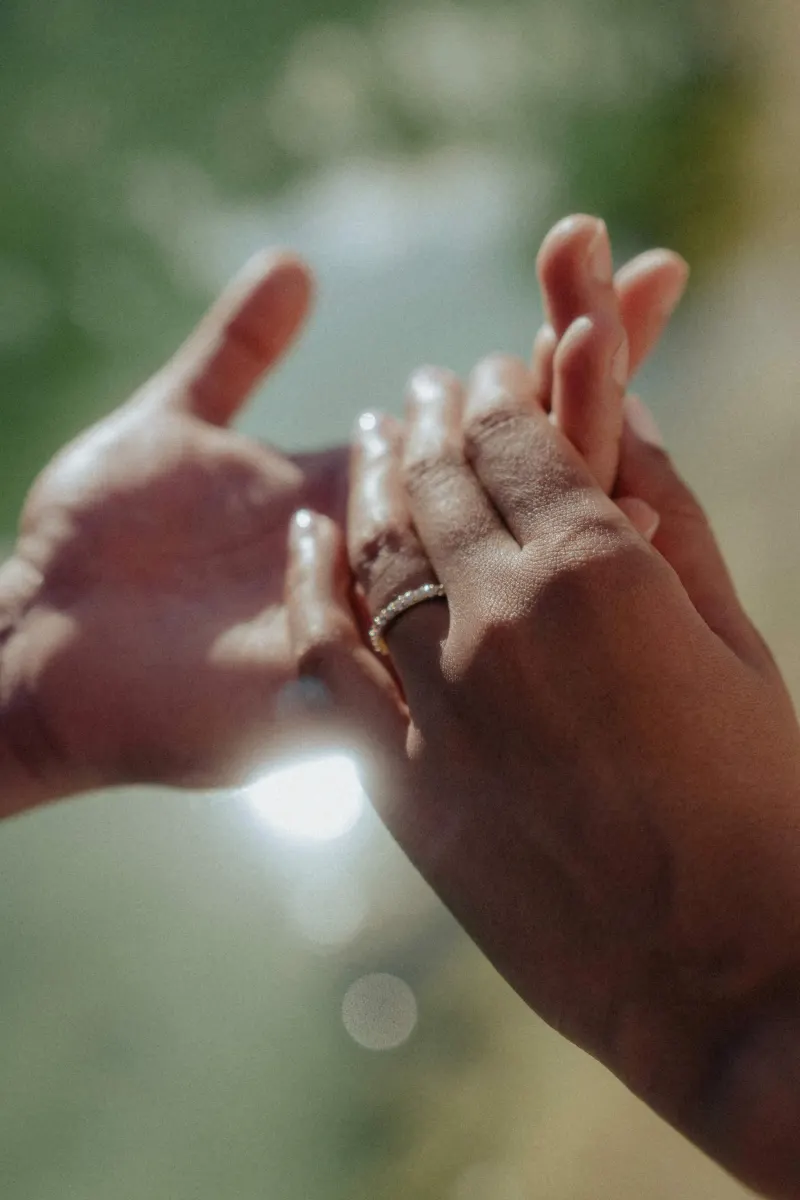 Close-up of a couple’s hands intertwined, engagement ring sparkling in natural light during a couples photoshoot.