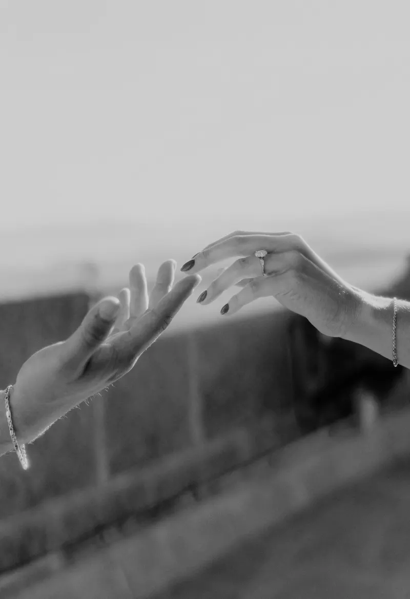 Close-up of a couple’s hands reaching for each other, her engagement ring catching the light during a romantic session.