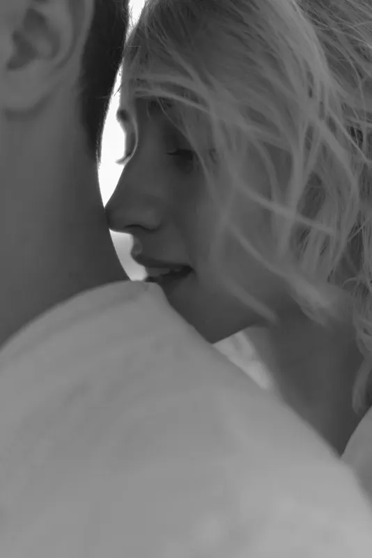 Close-up of a woman softly nuzzling her partner’s neck, capturing intimacy during a couples & engagements session.