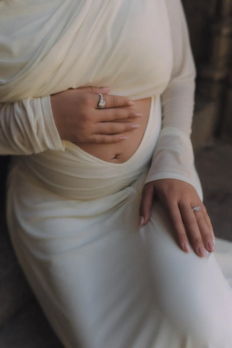 Close-up of an expectant mother in a white gown cradling her belly, captured during a Vacation Portraits shoot.