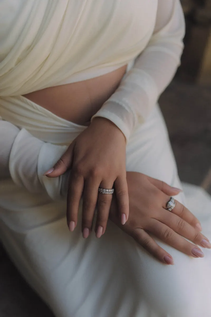 Close-up of an expectant mother’s hands resting on her belly, highlighting rings during a Vacation Portraits shoot.