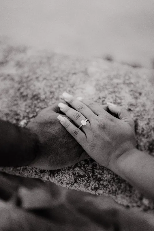Close-up of couple’s hands resting together on stone, highlighting an engagement ring during a couples photoshoot session.