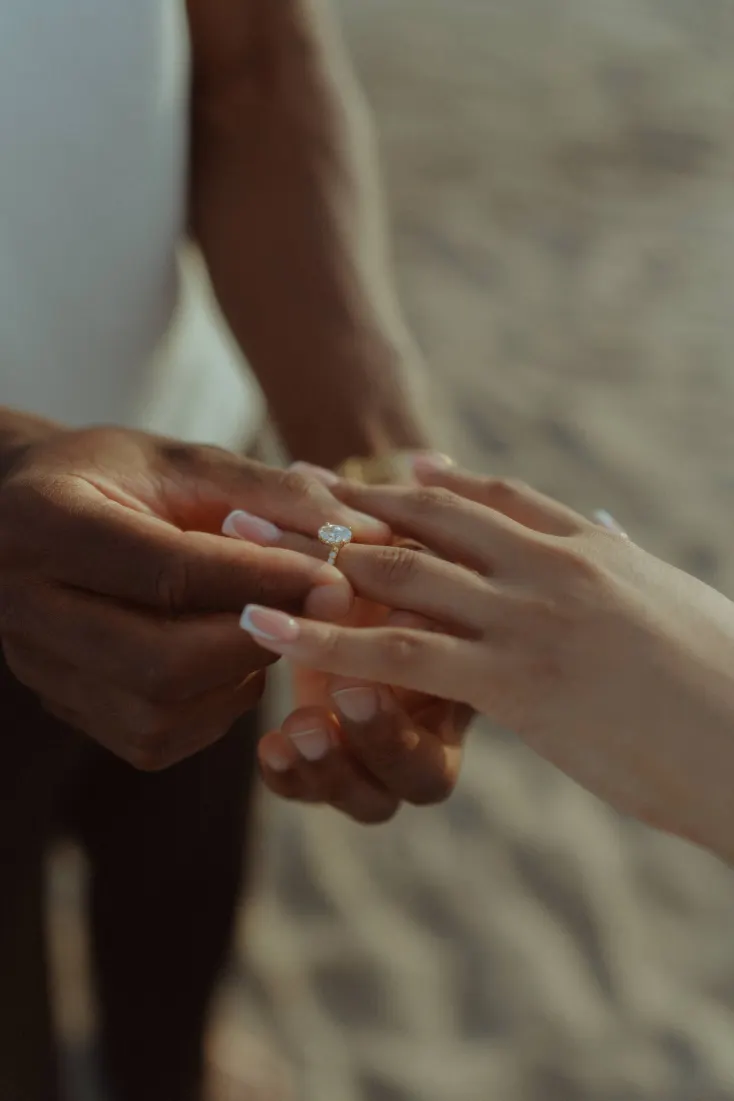 Close-up of Dexter placing the engagement ring on Cheryl’s finger during their Castelldefels Beach proposal.