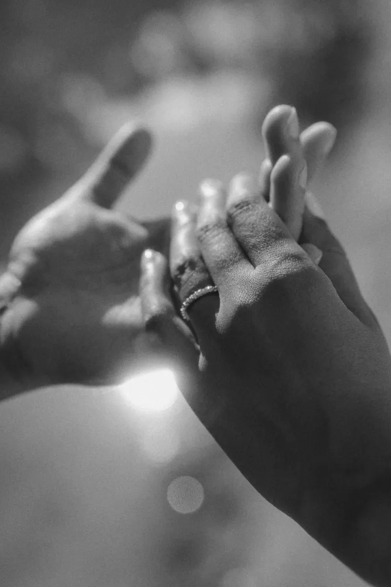 Close-up of intertwined hands, engagement ring sparkling, capturing a tender moment from a couples photoshoot.