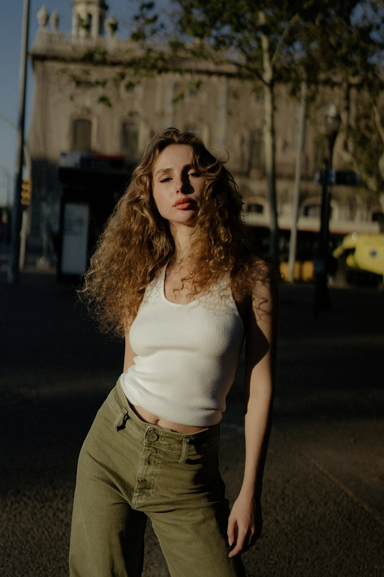 Confident woman stands in soft evening light on a European street during a Vacation Portraits photoshoot.