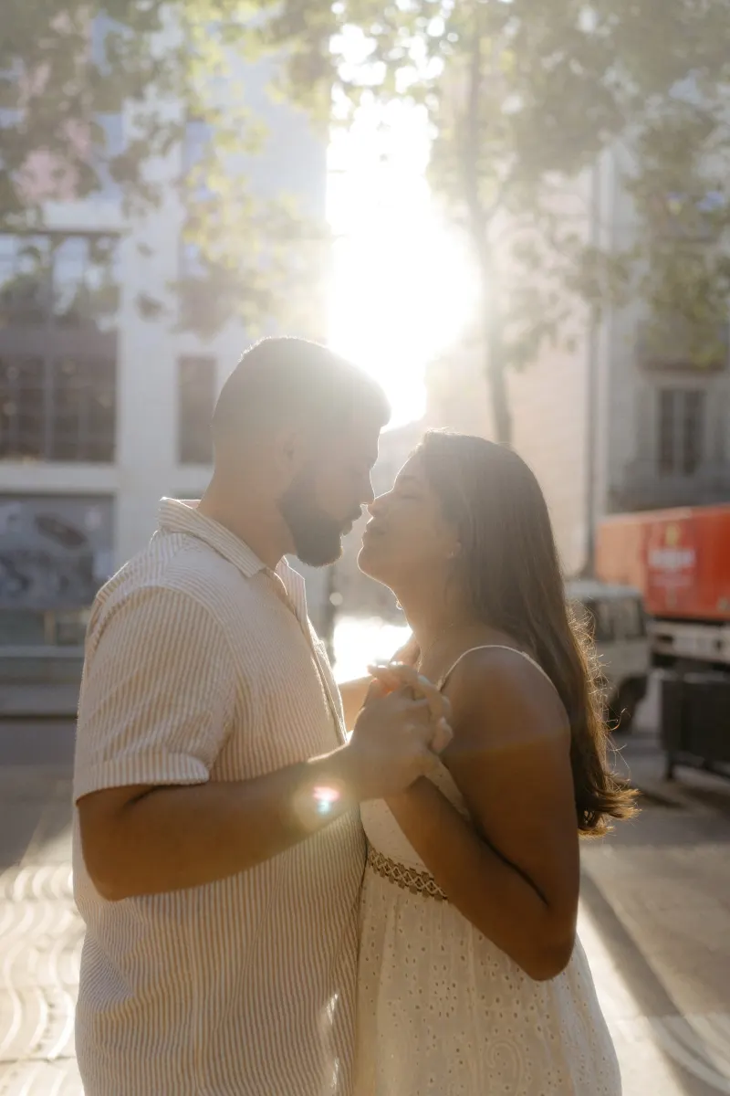 Couple dances close in golden sunlight on a city street, sharing a romantic moment during their engagement session.