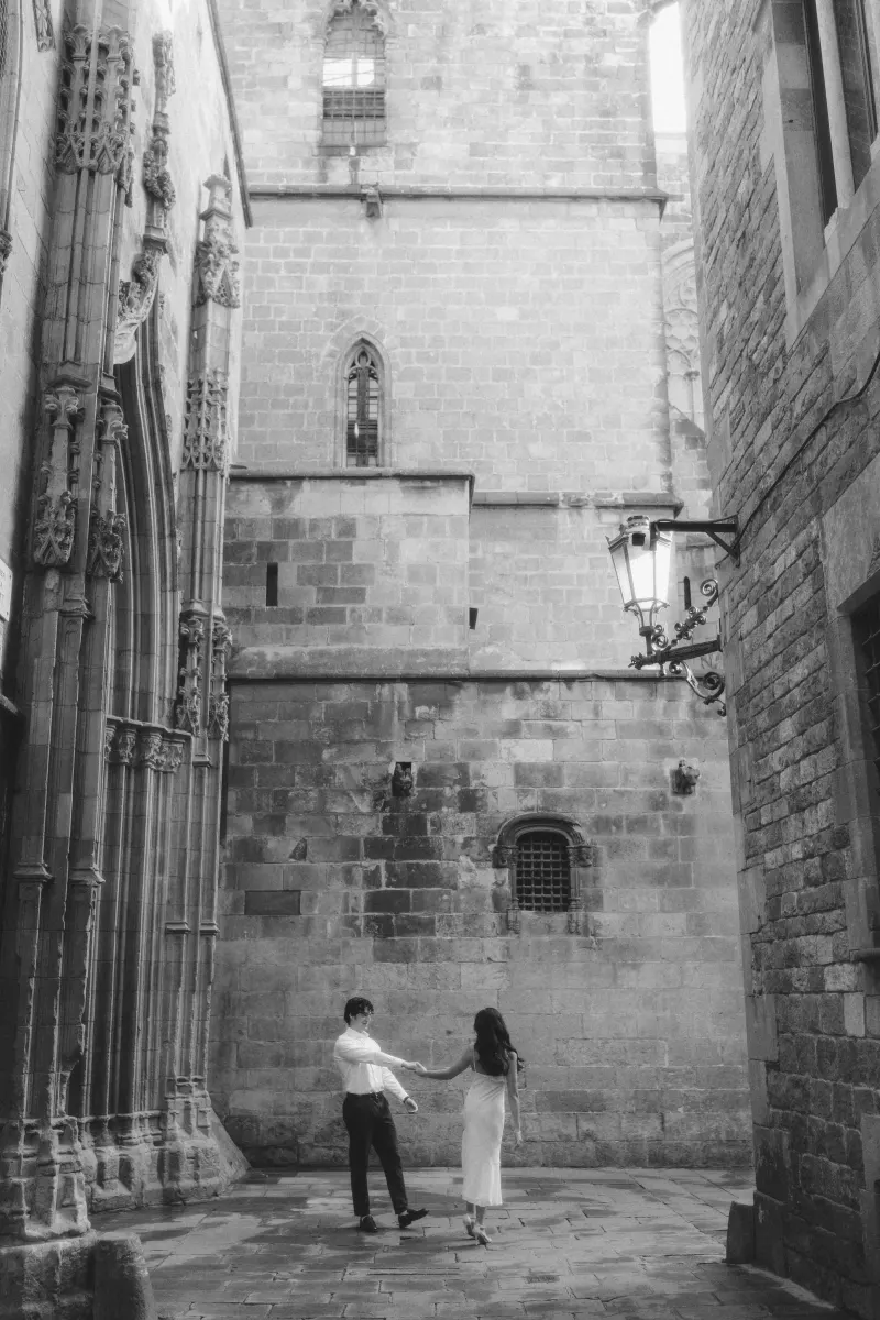 Couple dances together in a quiet Gothic Quarter alley, sharing a romantic moment during their engagement photoshoot.