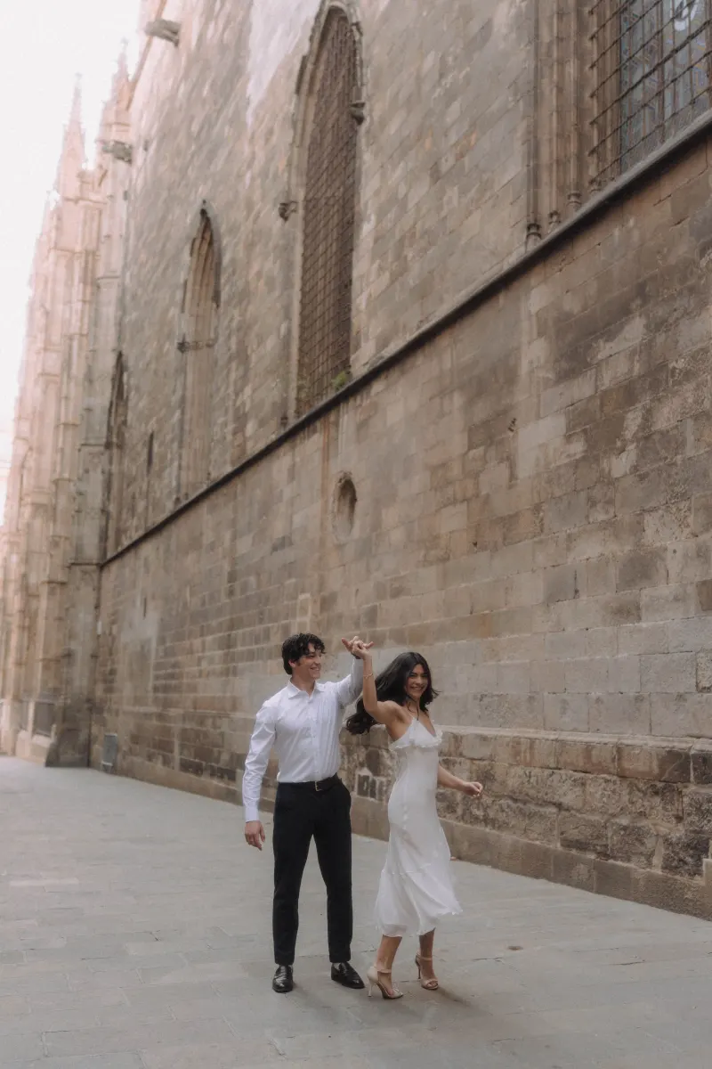 Couple dancing and laughing together along a historic stone wall during a couples & engagements photoshoot.